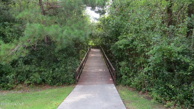 This lovely wooded, over a half acre, lot overlooks the 4th tee on Carolina National Golf Club in North Carolina - for sale on GolfHomes.com, golf home, golf lot